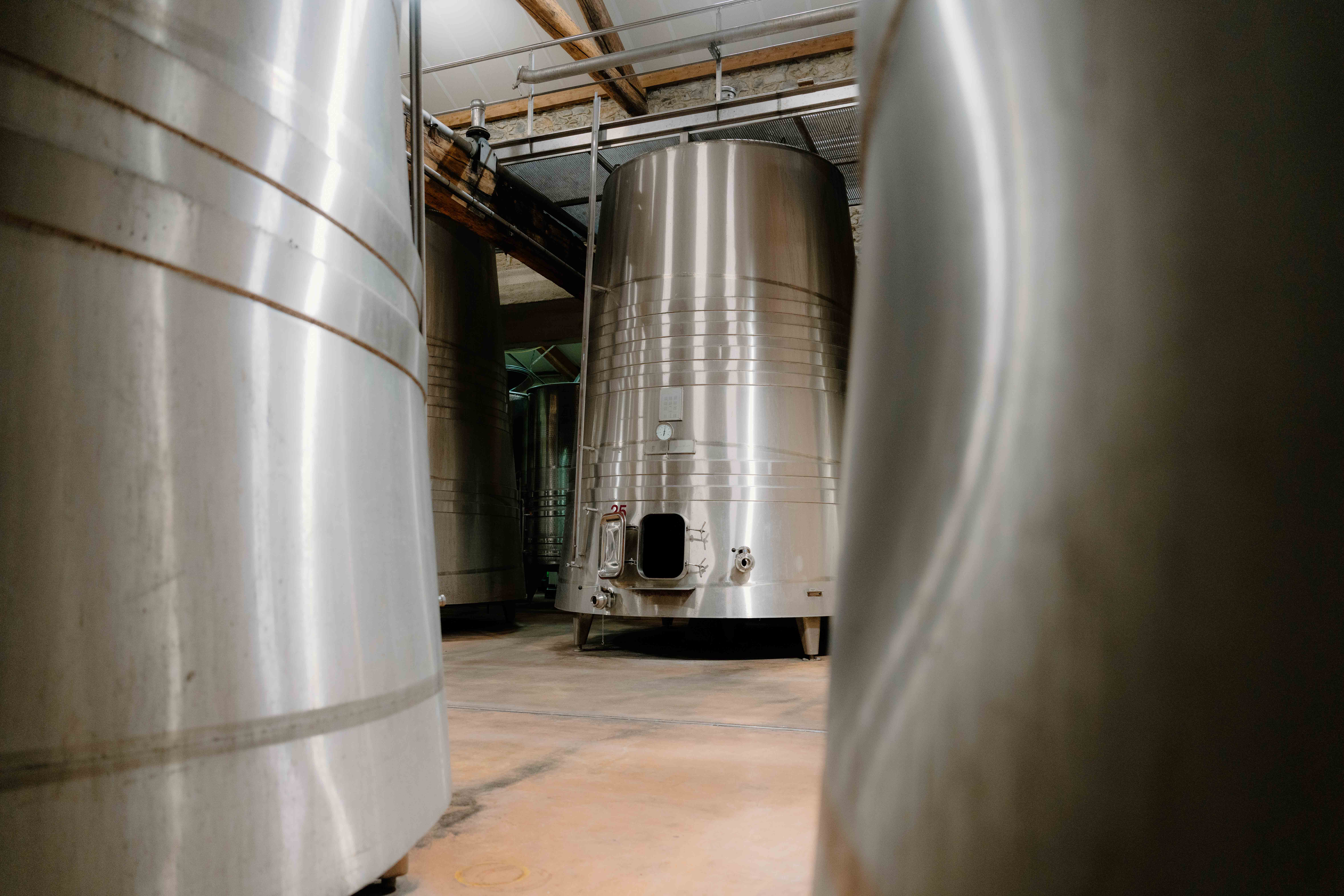 Three large silver whisky stills in a distillery